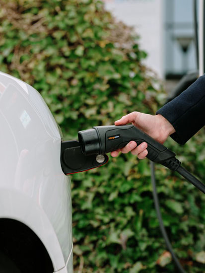 EV driver plugging in charger in front of office building